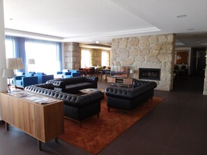 A spacious living area with a stone wall, a television, and a fireplace. - Belmonte Sinai Hotel (Belmonte)