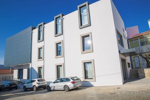 A modern building with multiple windows and a paved ground.