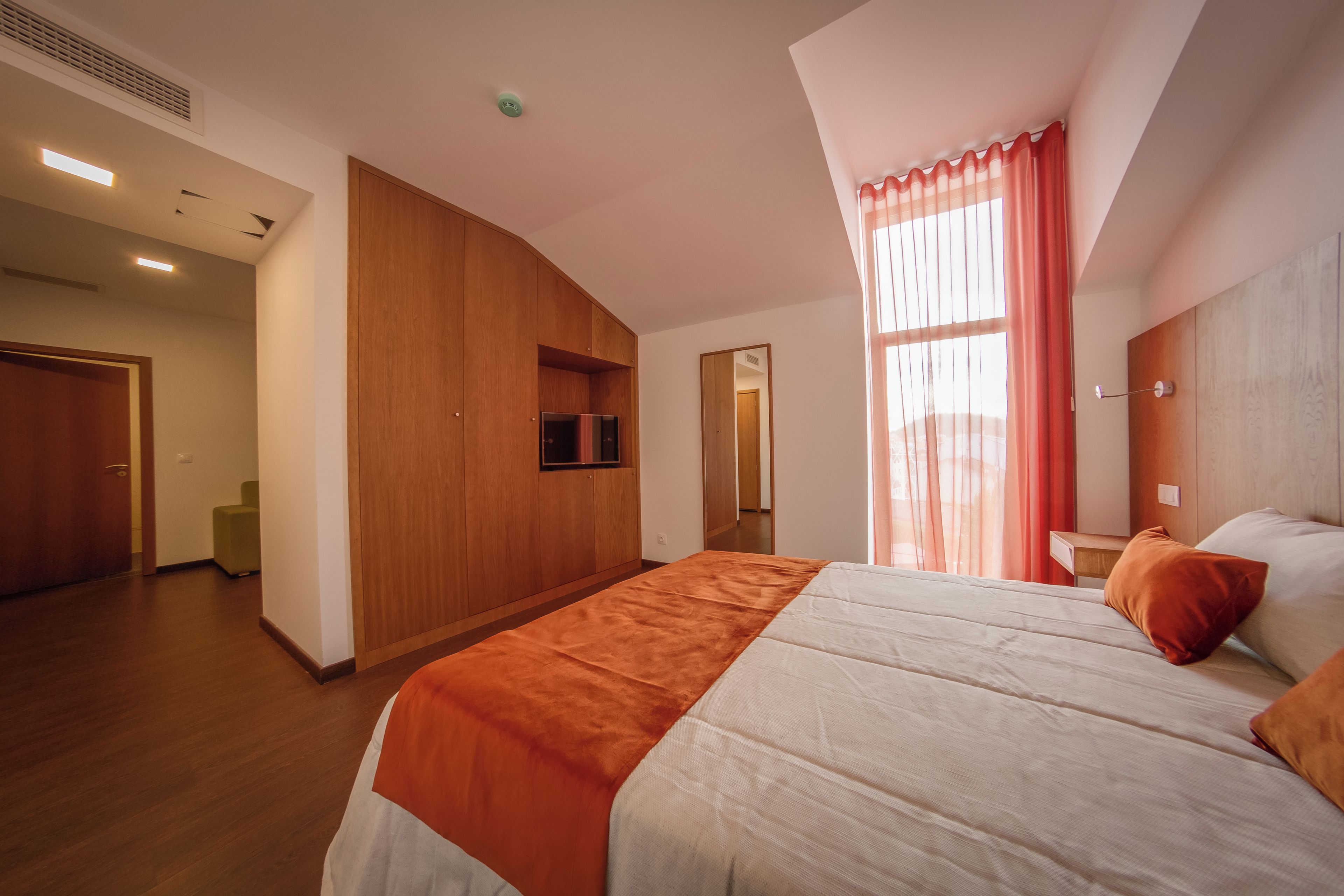 A modern hotel room with a large bed, a television, and a view of the outdoors.