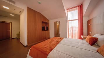 A modern hotel room with a large bed, a television, and a view of the outdoors.