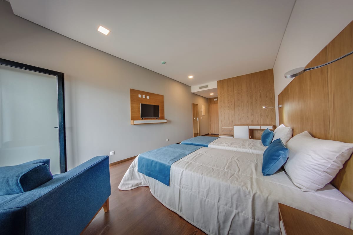 A modern hotel room with a large bed, a desk, and a chair.