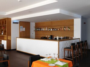 A restaurant with a bar area, wooden paneling, and a table set with wine glasses and plates. - Belmonte Sinai Hotel (Belmonte)