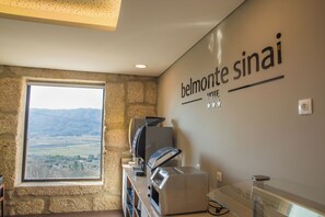 A hotel interior with a stone wall, a window with a view, a coffee machine, and a wall sign reading 'belmontte sinai HOTEL'. - Belmonte Sinai Hotel (Belmonte)