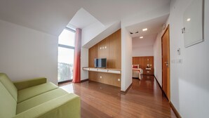 Un soggiorno moderno con un divano, una TV, mobili in legno e un angolo cottura sullo sfondo.