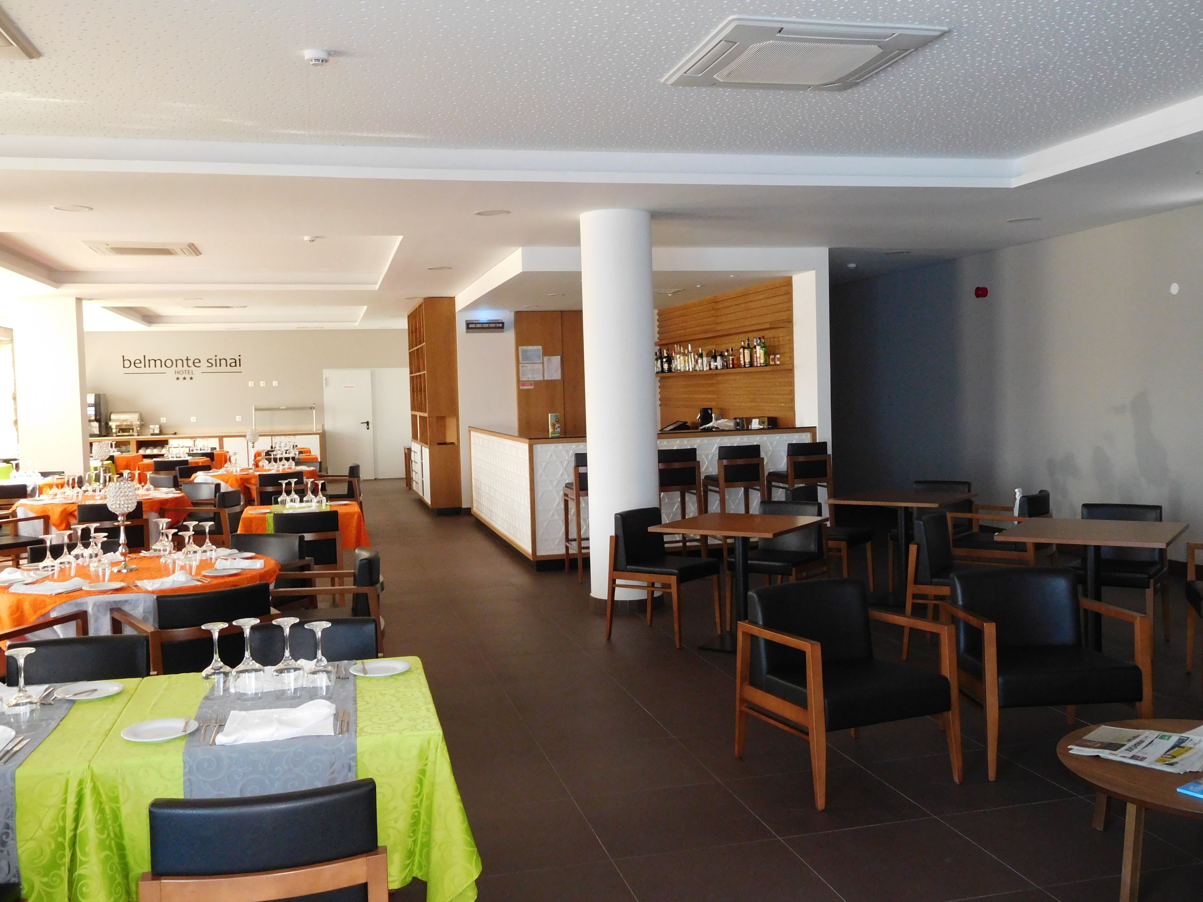 A hotel restaurant with multiple dining areas, a bar, and a reception desk.