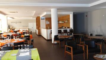 A hotel restaurant with multiple dining areas, a bar, and a reception desk.