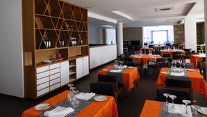Un ristorante con diversi tavoli, una vetrina per vini e un muro in pietra sullo sfondo.