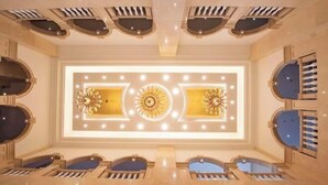 A luxurious hotel lobby with a central chandelier, mirrored walls, and a symmetrical ceiling design. - Venus Royal Hotel (Guilin Airport) (Guilin)