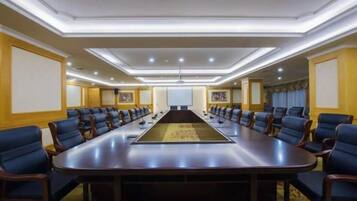 Une salle de conférence équipée d’une longue table, de nombreuses chaises et d’un écran de projection.