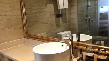A bathroom with a large mirror, a white sink, and a glass shower enclosure.