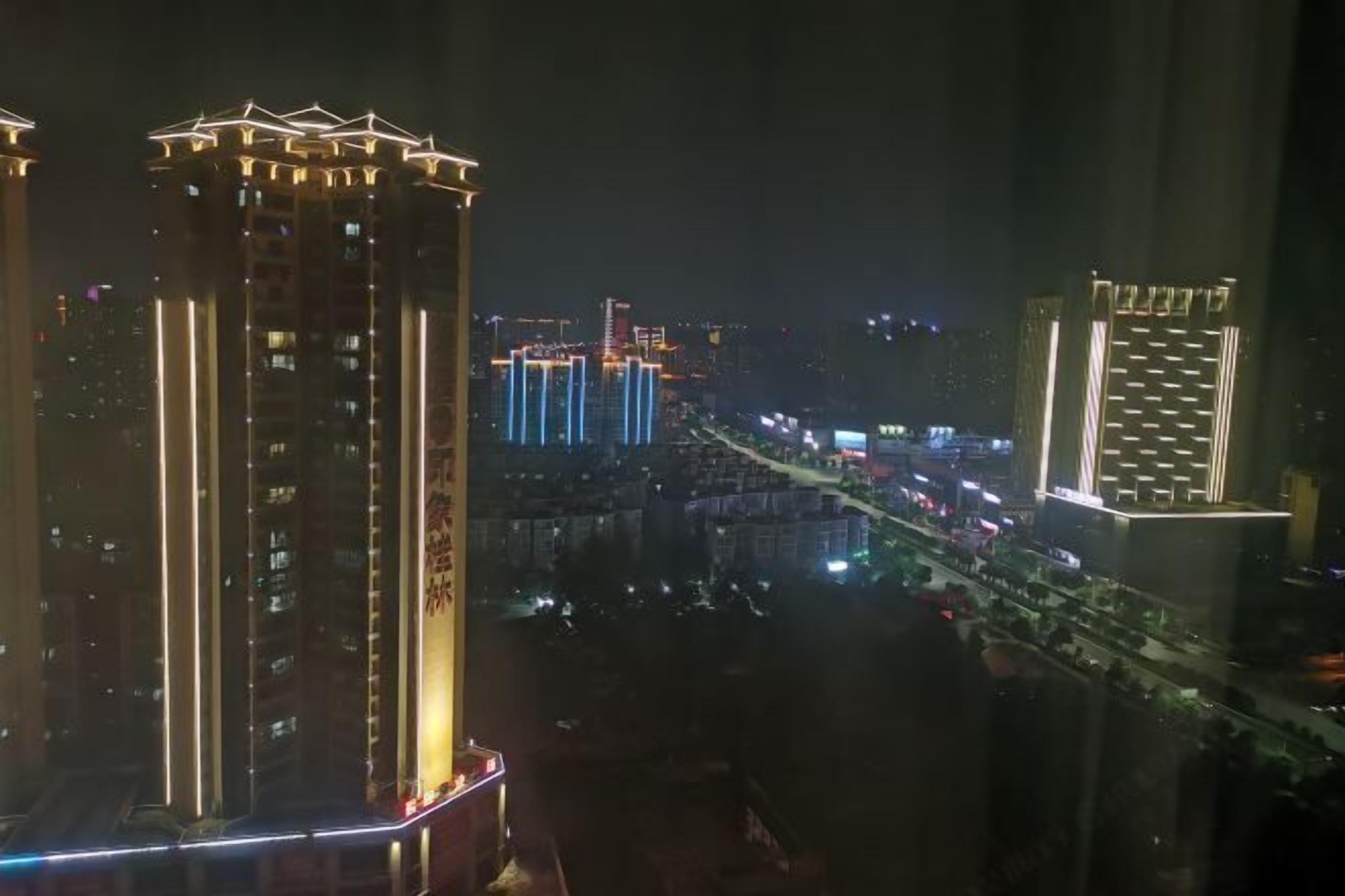 A high-rise building with illuminated vertical lines and a prominent sign.