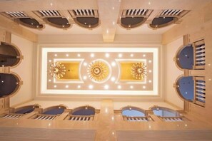 En hotellobby med en stor kristallkrona i mitten, en sittgrupp och ett tak med ventilationssystem.