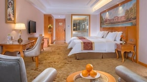 A hotel room with a bed, two bedside tables, a desk, a chair, a television, and a painting on the wall. - Venus Royal Hotel (Guilin Airport) (Guilin)