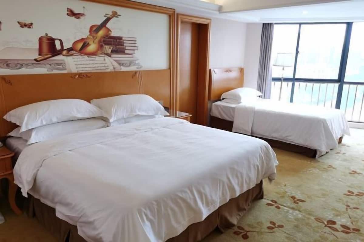 A hotel room with two beds, a large window with a view, and a wall with a musical instrument and books.