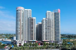 Un hôtel à plusieurs étages, doté d’un design moderne, avec une entrée imposante et un drapeau au sommet.