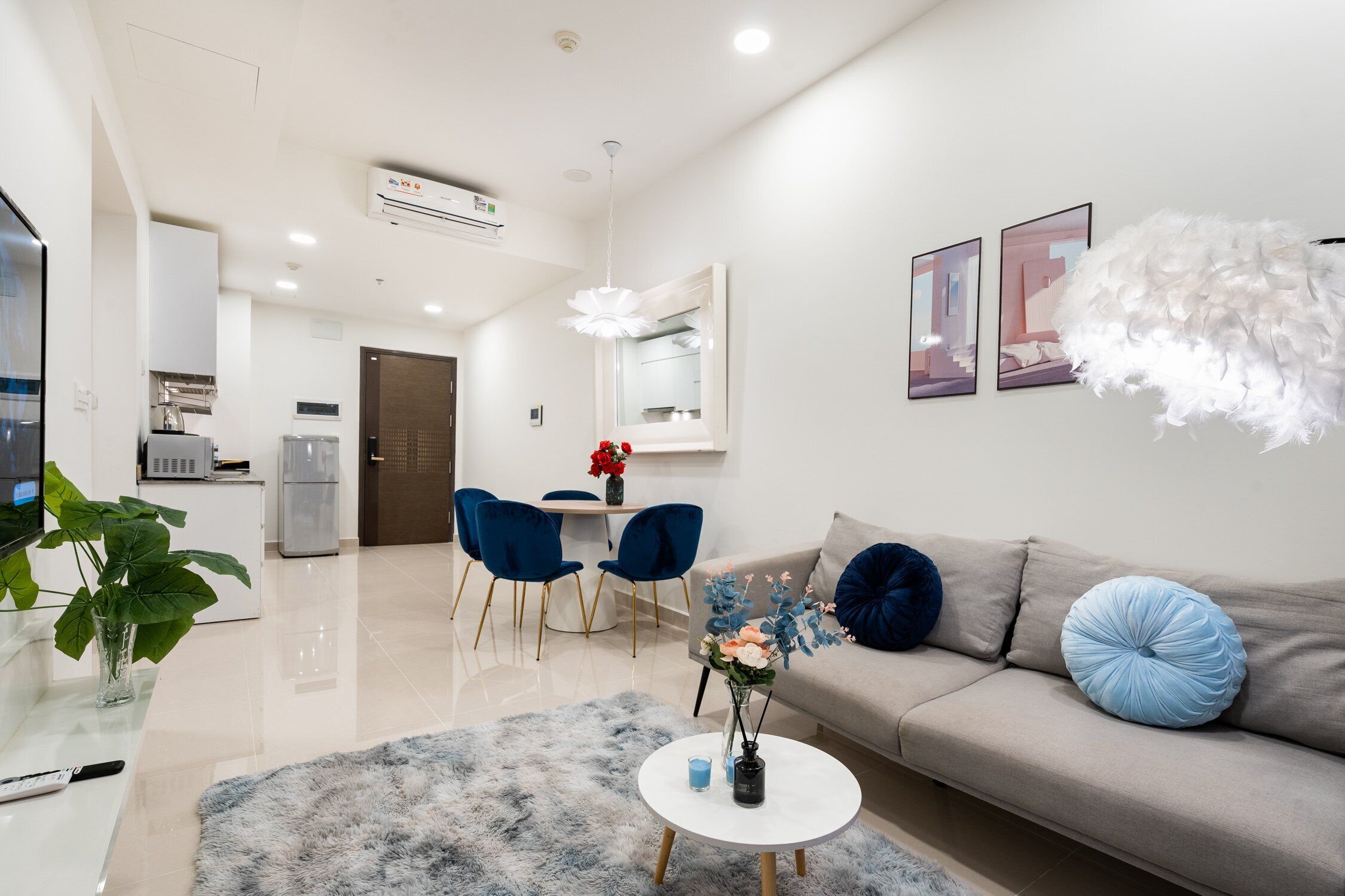 Una sala de estar moderna con un sofá, una mesa de centro y sillas. Hay un comedor con una mesa y sillas. Un equipo de aire acondicionado está montado en la pared.