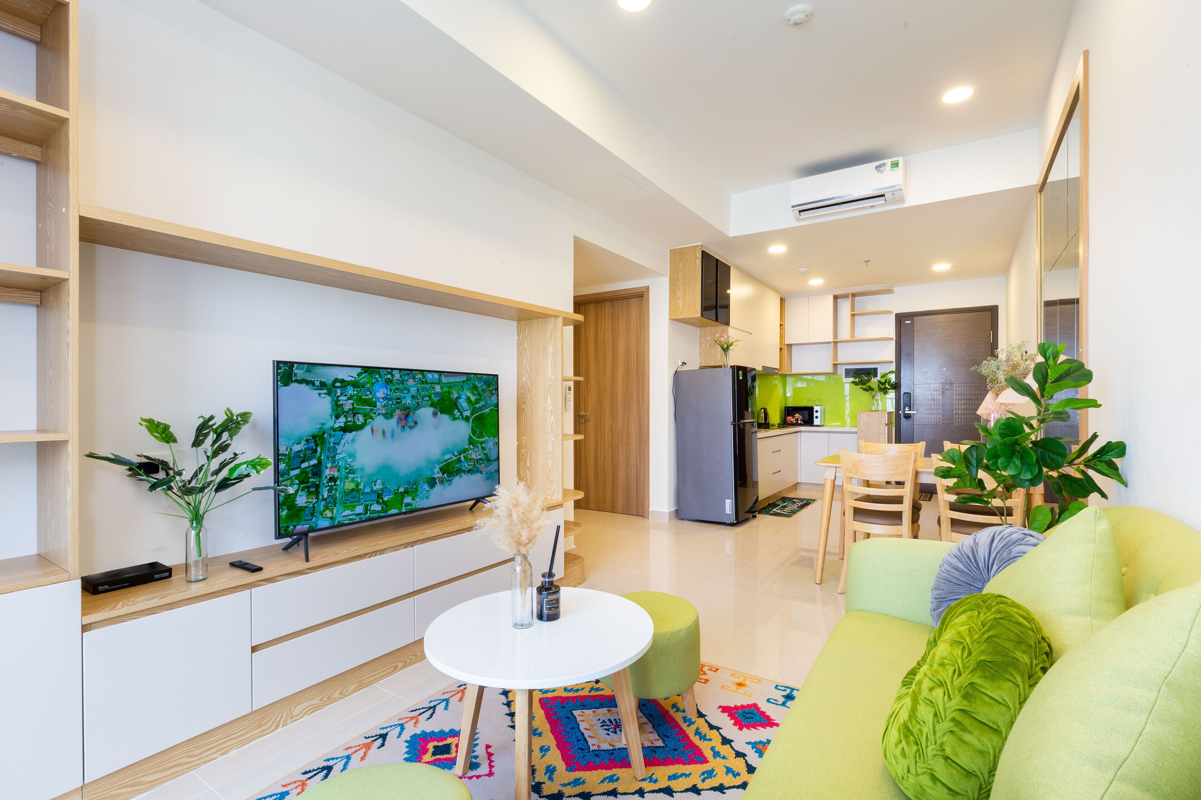 Een moderne woonkamer met een flatscreen televisie, een ronde salontafel en een groene bank.