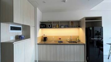 Una cocina moderna con alacenas de madera clara, encimera de granito, refrigerador negro y horno empotrado.