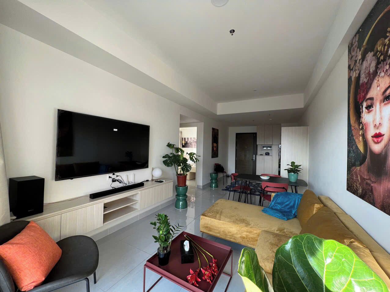 A modern living room with a flat-screen TV, a sofa, a coffee table, and a dining area with chairs and a table.