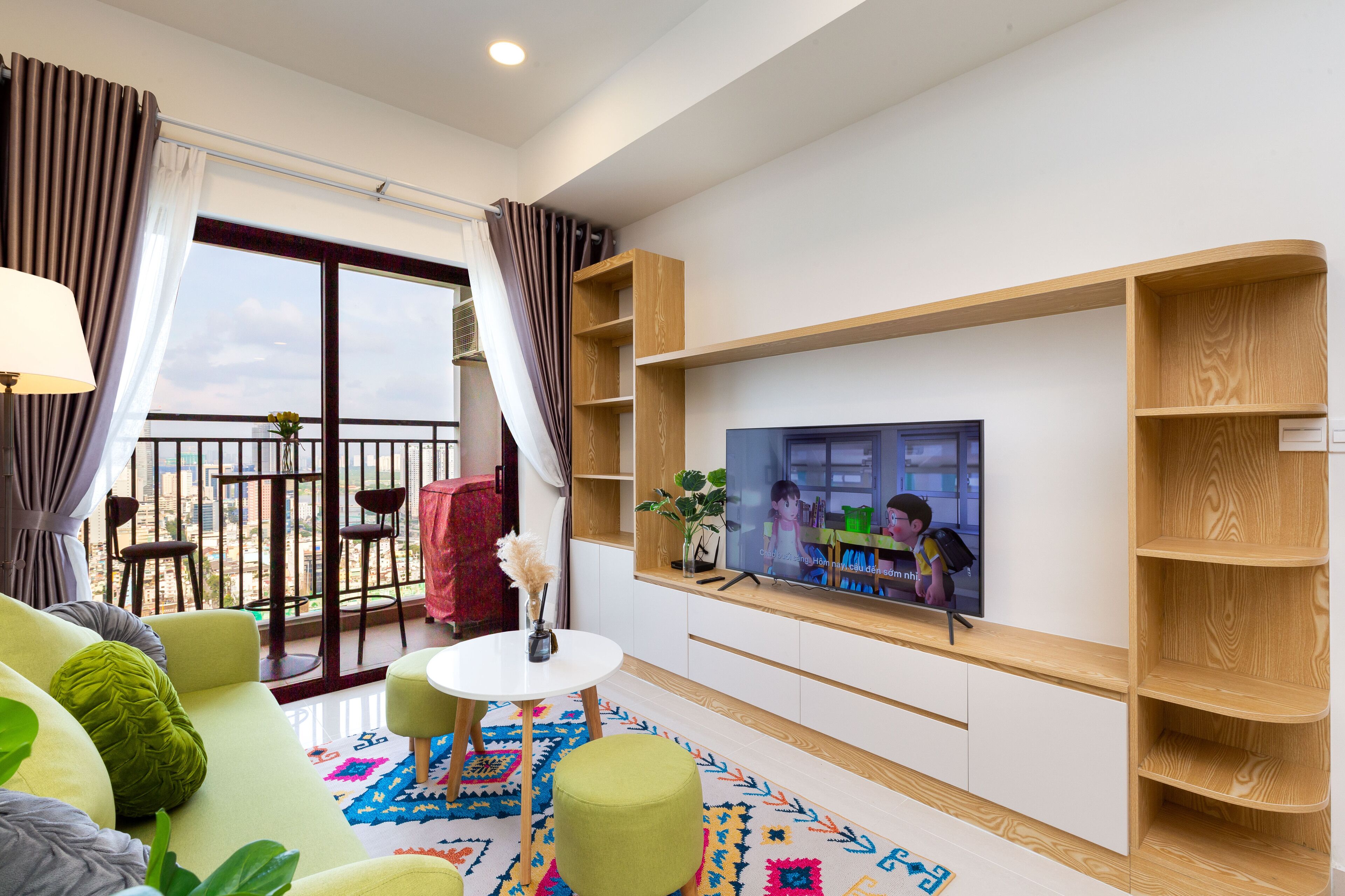 Ein modernes Wohnzimmer mit einer Couch, einem Fernseher und einem Balkon mit Stühlen.