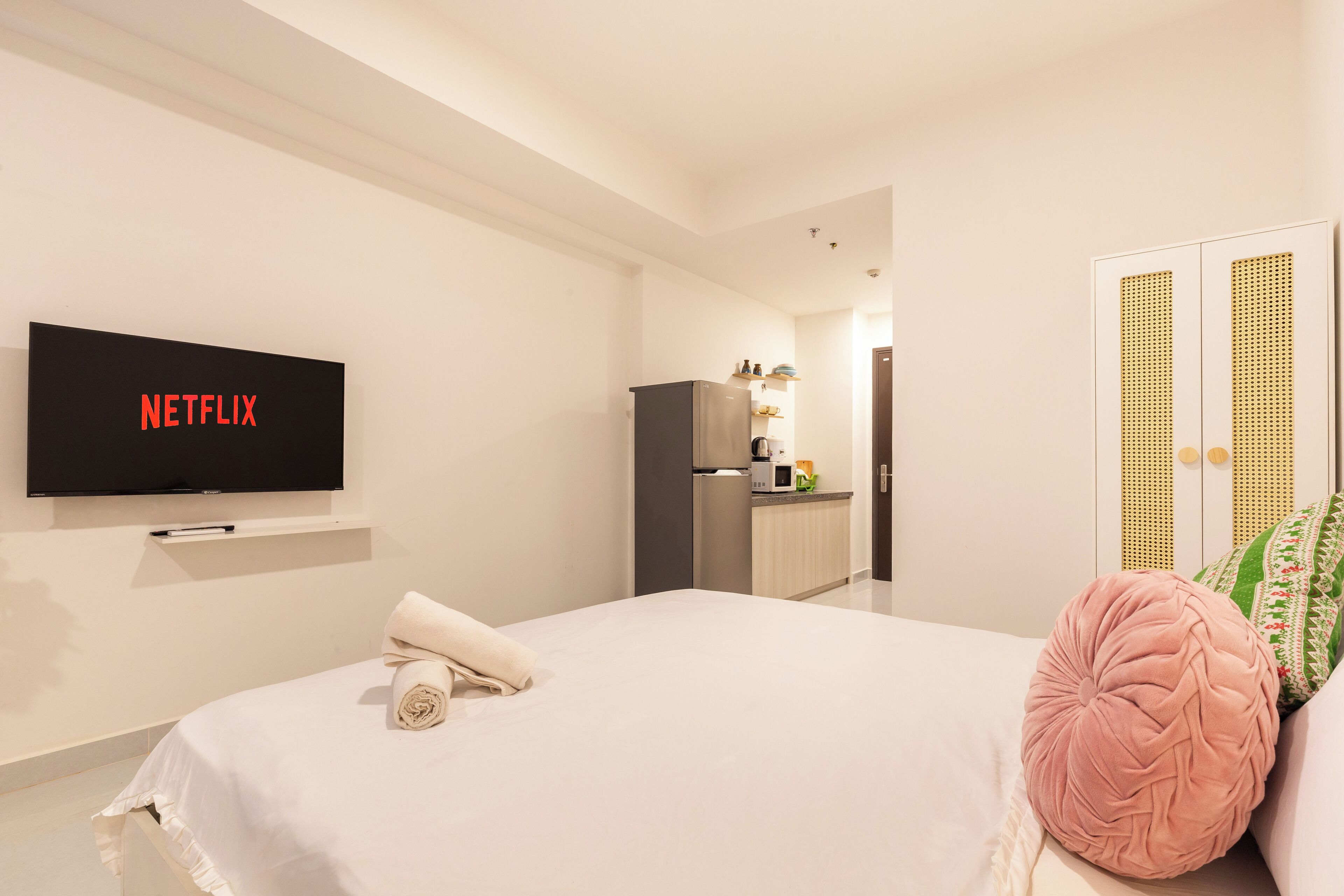 Una habitación de hotel moderna con cama, televisor montado en la pared, kitchenette y un armario de diseño único.