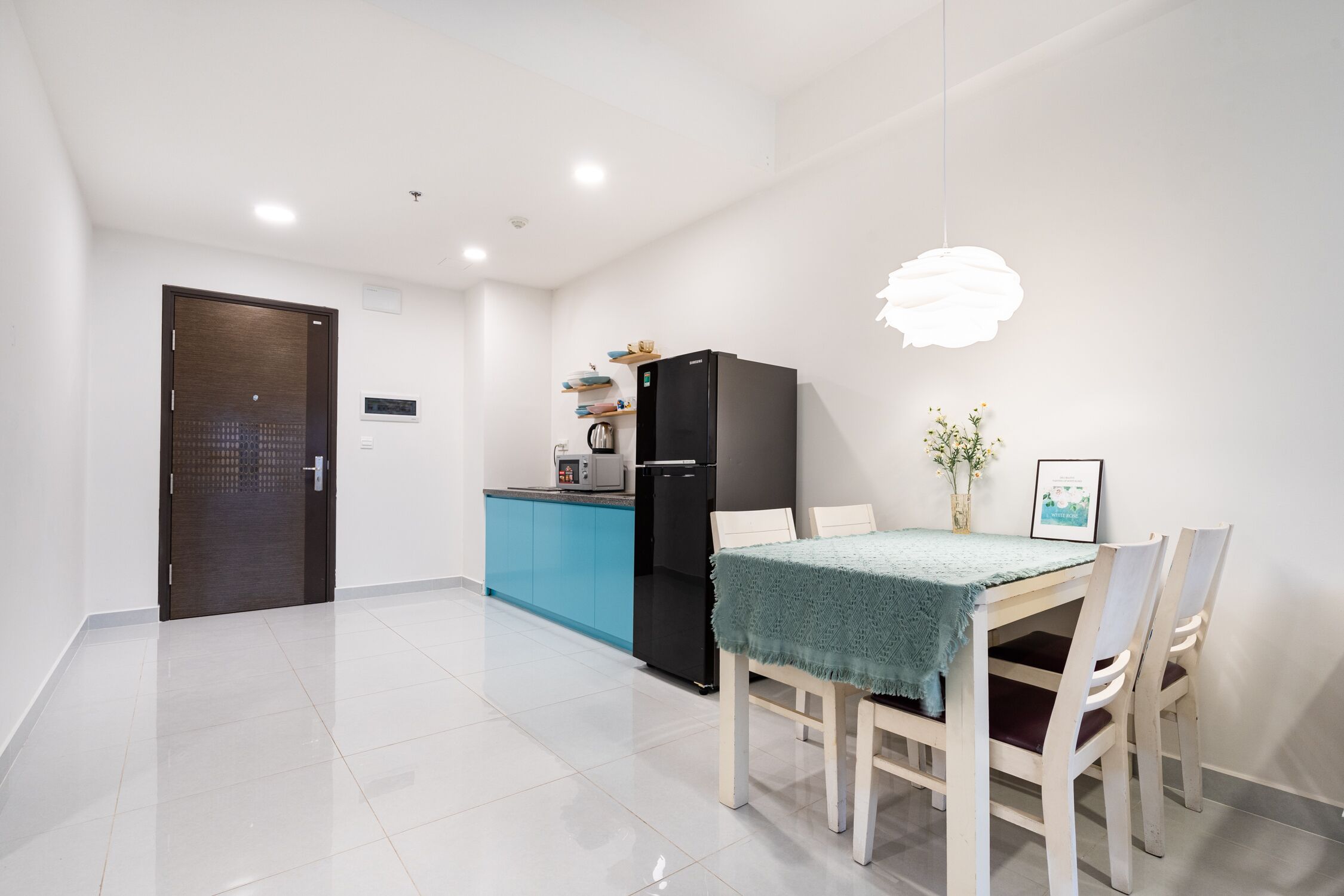 A modern kitchen with a black refrigerator, a blue countertop, and a dining area with a table and chairs.