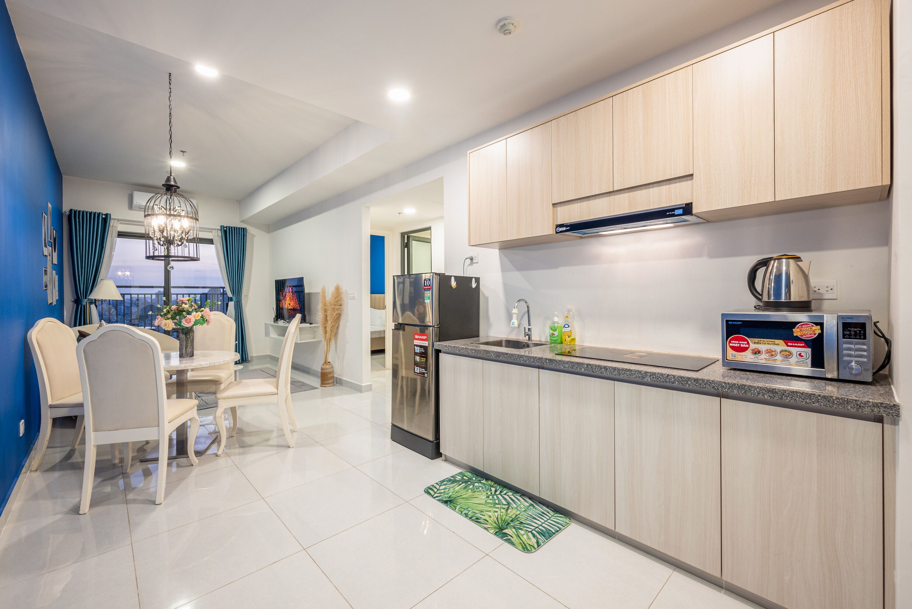 A modern kitchen with wooden cabinets, a stainless steel refrigerator, a microwave, and a sink.