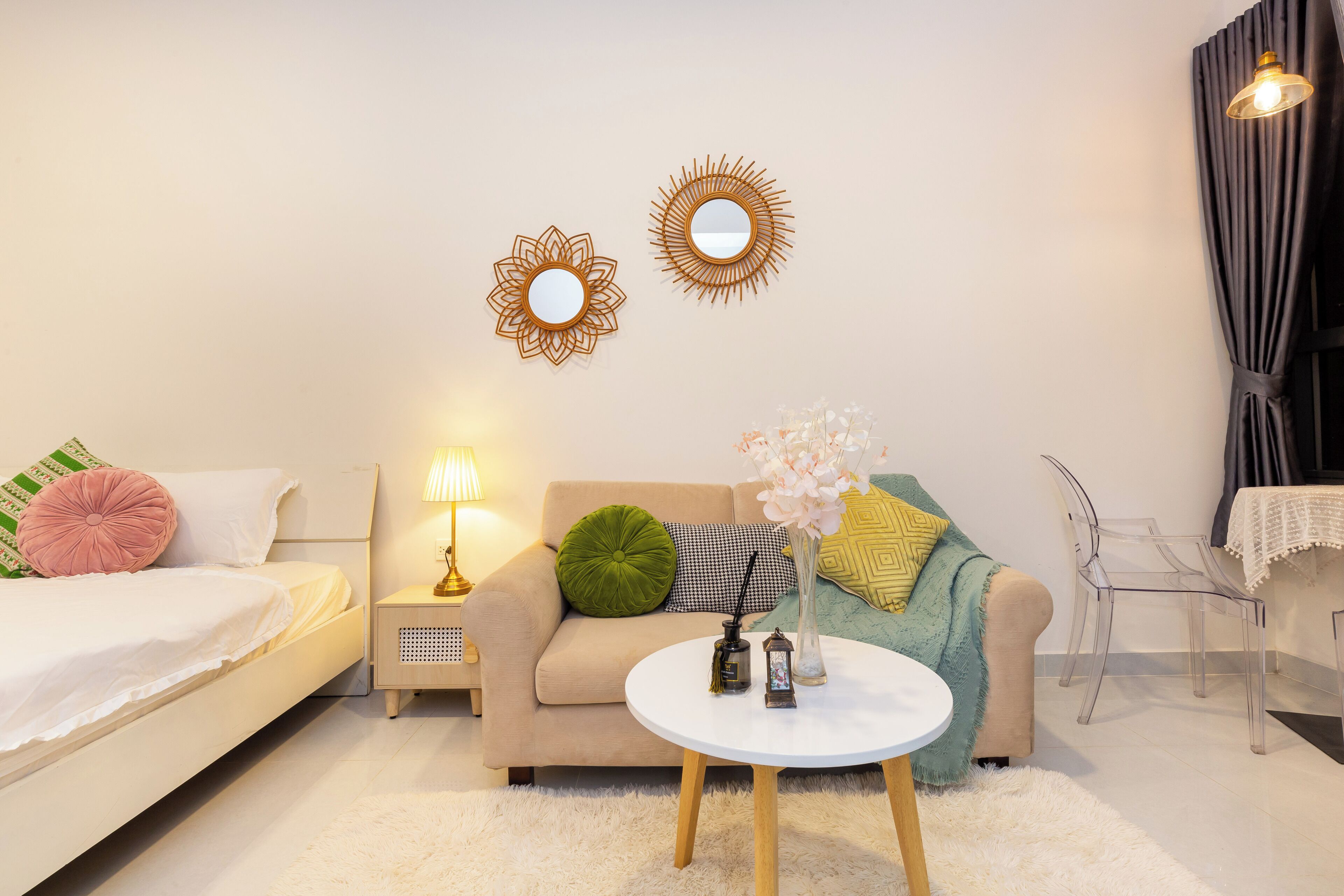 Un dormitorio moderno con cama, sofá, una mesa de centro y dos espejos en la pared.