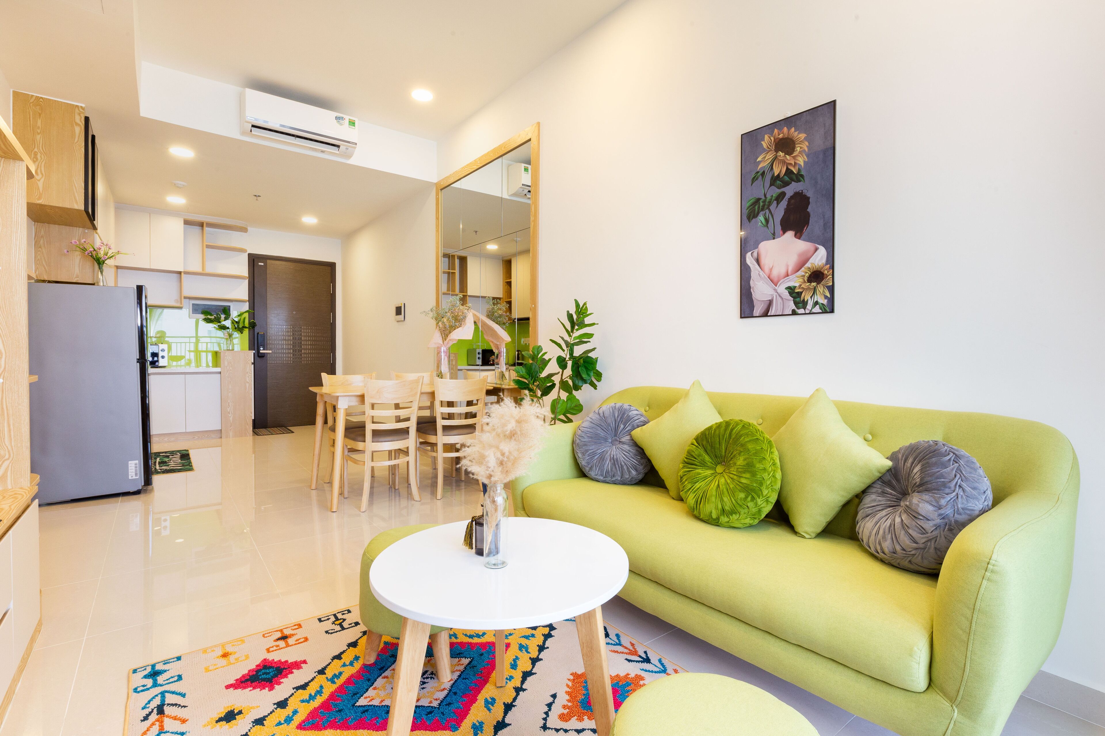A modern living room with a green sofa, a white coffee table, and a colorful rug.