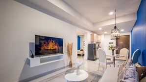 Ein modernes Wohnzimmer mit einem Flachbildfernseher, einem weißen Couchtisch und einem Sofa mit Kopfkissen mit Zeitungsmotiv.