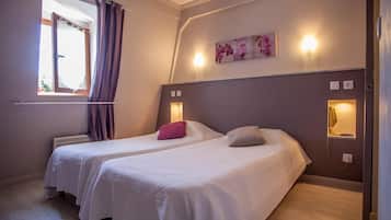 Habitación de hotel con dos camas, una ventana con cortinas, una lámpara de pared y un cuadro.