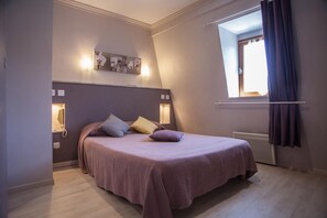 A bedroom with a bed, bedside lamps, a window with curtains, and a wall-mounted artwork. - Logis Auberge de L'ile (Jayac)