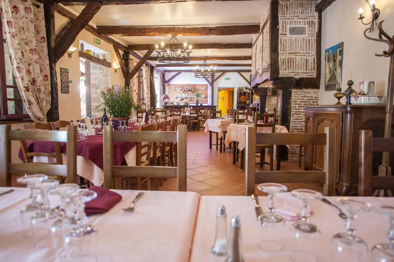 A restaurant with wooden beams, chandeliers, and tables set for dining.