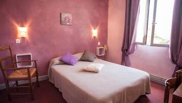 Un dormitorio con una cama, dos luces fijadas a la pared, una ventana con cortinas y una silla.