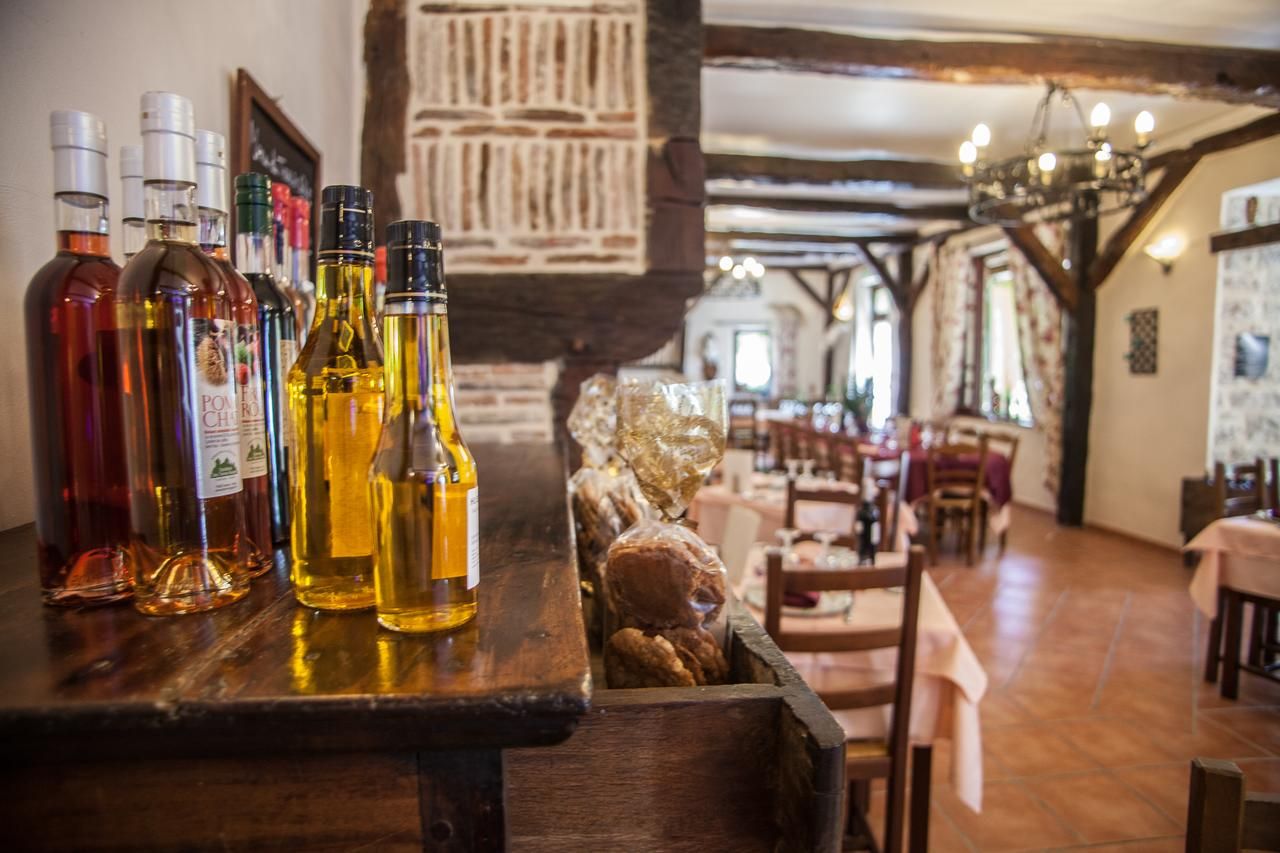 A bar area with various bottles of liquor, wooden furniture, and a rustic interior with exposed beams and stone walls.