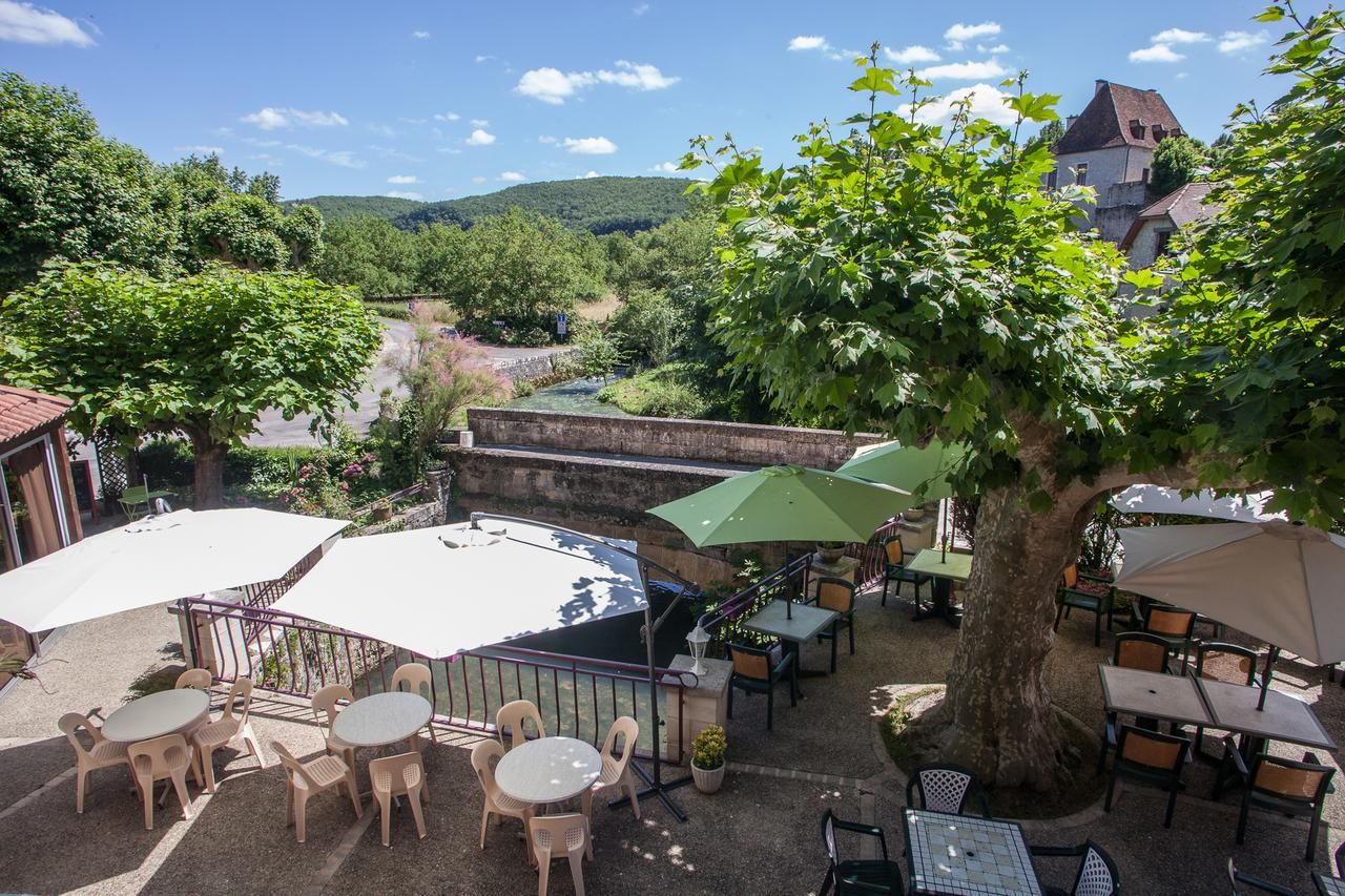 An outdoor patio with tables and chairs, surrounded by trees and overlooking a valley.