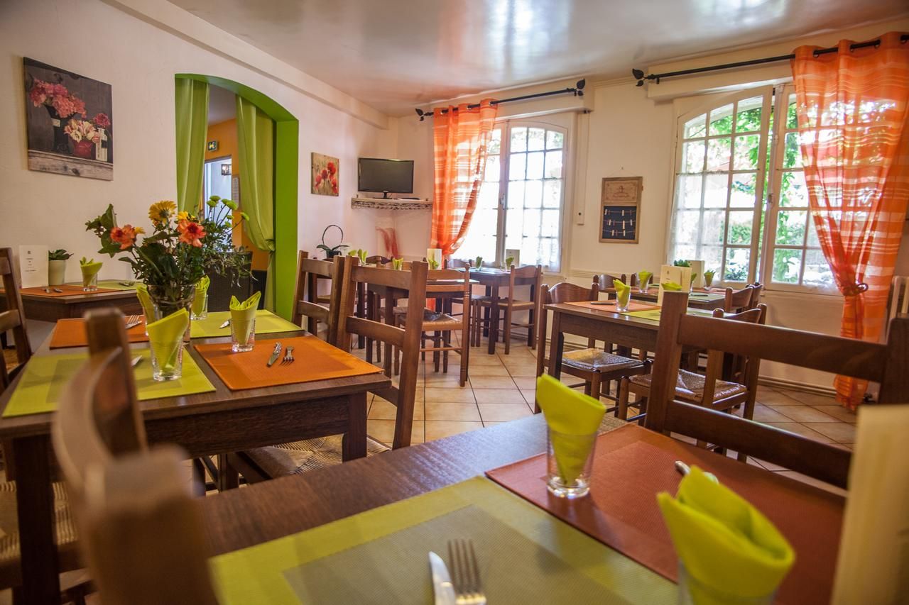 Un comedor con varias mesas y sillas, un televisor montado en la pared y una ventana con cortinas.
