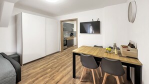 Eine moderne Küche mit weißen Schränken, einem Holztisch und einem an der Wand befestigten Flachbildfernseher.
