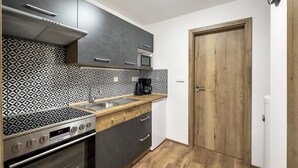 Eine kleine Küche mit Herd, Backofen, Mikrowelle und Kaffeemaschine.