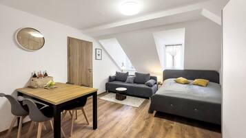 A compact, modern apartment with a dining area, a sofa, and a bed.