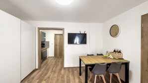 Ein moderner Essbereich mit Holztisch und Stühlen, einem an der Wand befestigten Flachbildfernseher und einer Uhr.