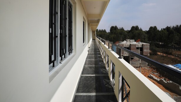 Un couloir doté de grandes fenêtres et d’un balcon donnant sur un chantier de construction.