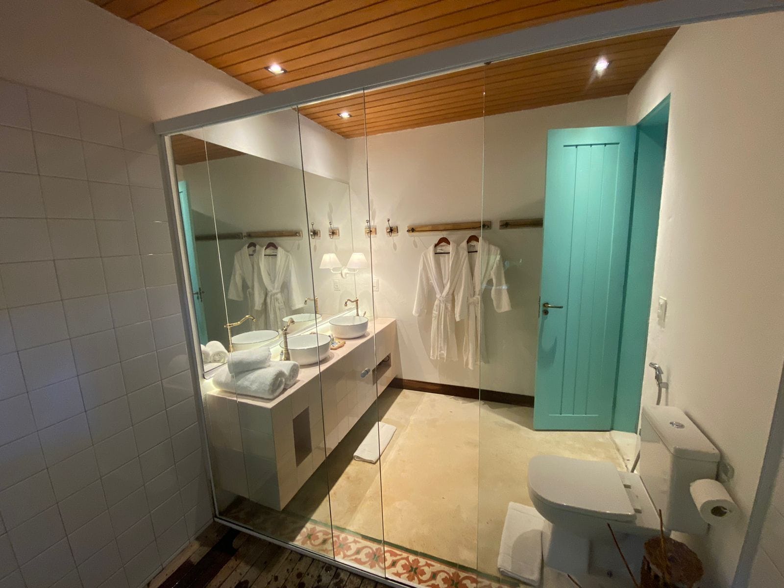 A modern bathroom with a glass shower enclosure, a large mirror, a vanity with two sinks, and a toilet.