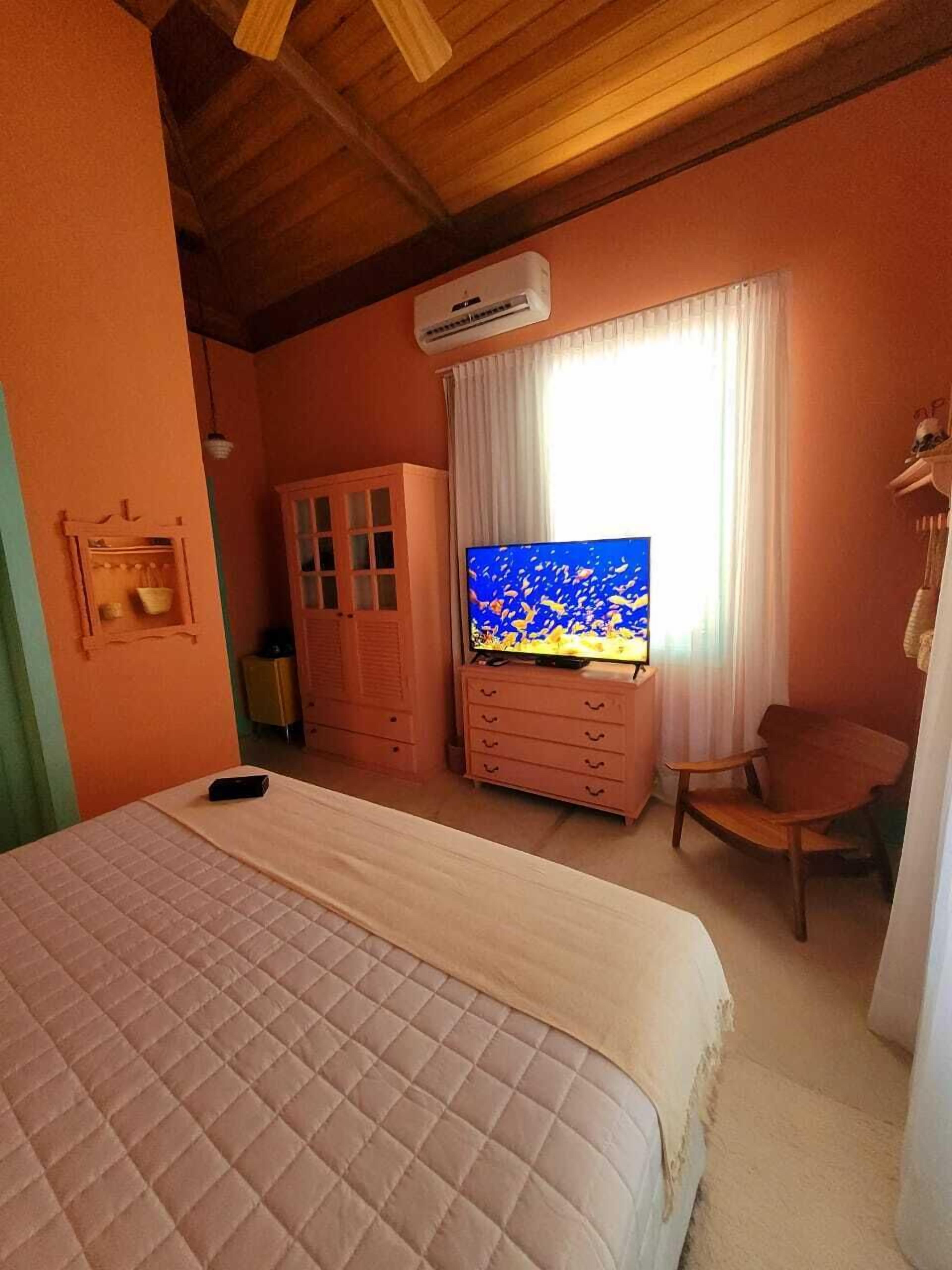 Een slaapkamer met een bed, een televisie, een kledingkast en een stoel.