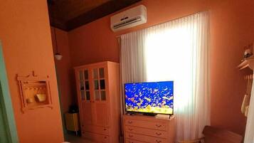 Een slaapkamer met een bed, een televisie, een kledingkast en een stoel.
