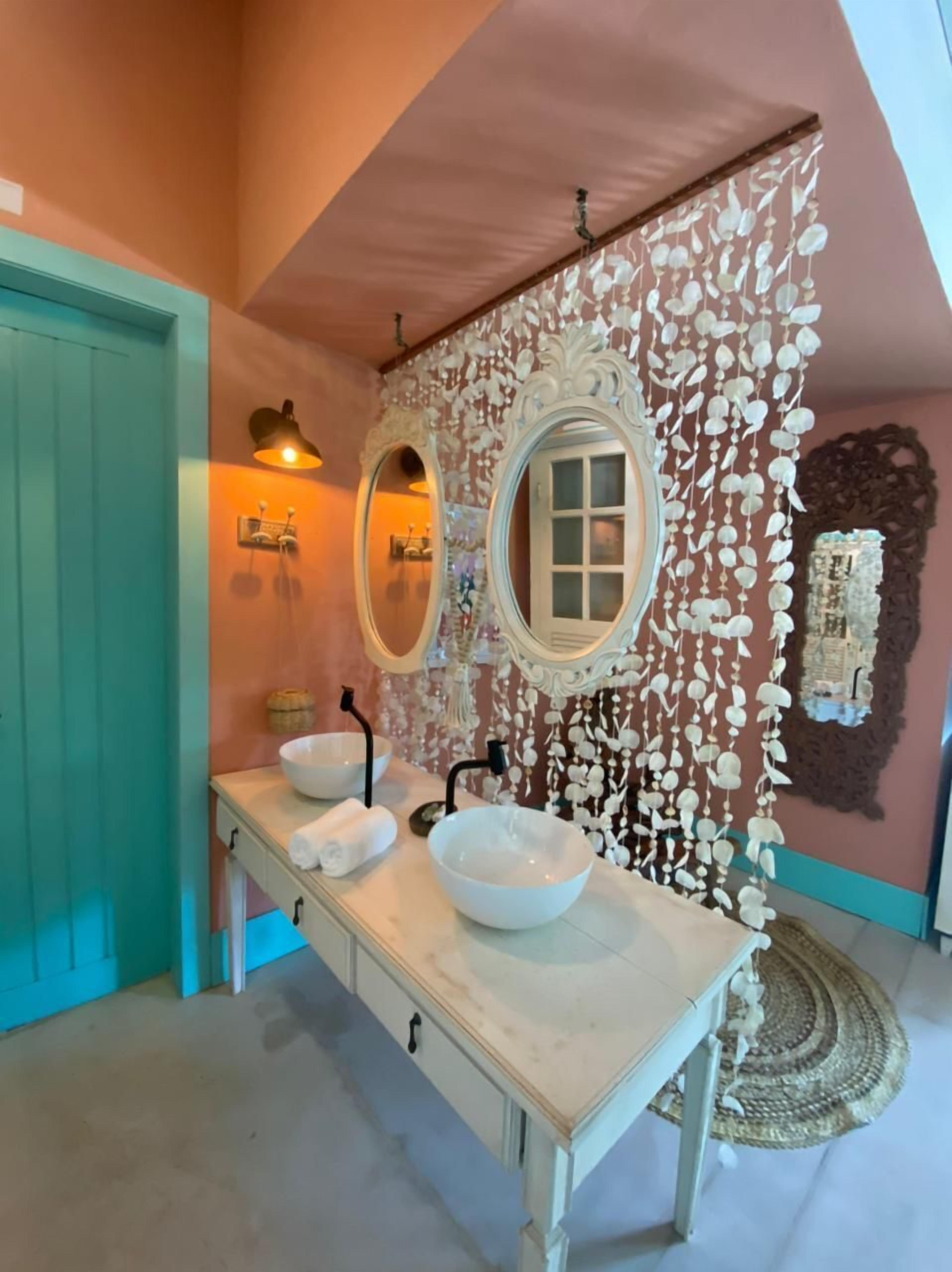 Un baño con un tocador amplio, dos espejos y un detalle decorativo en la pared.