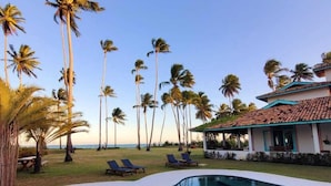 A swimming pool with a star design, surrounded by palm trees and lounge chairs, with a building in the background. - Casa Brasileira - Hotel Galeria (Porto de Pedras)