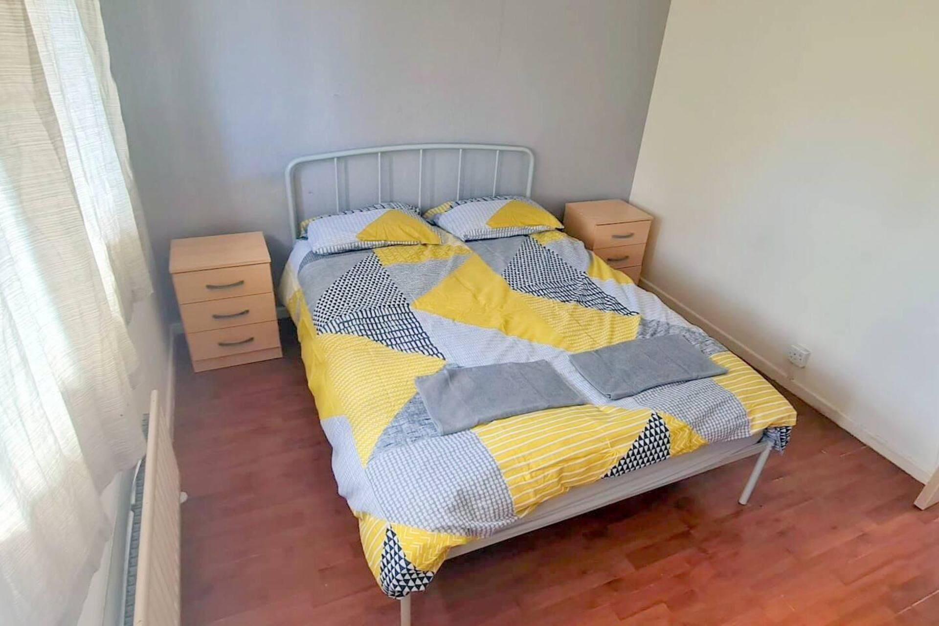 A single bed with a metal frame, a wooden nightstand on each side, and a plain wall.
