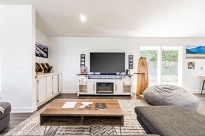 Een moderne woonkamer met een flatscreen televisie, witte kasten en een open haard.