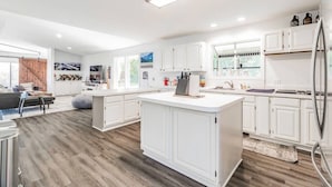 Een moderne keuken met witte kasten, een centraal eiland en een groot raam.